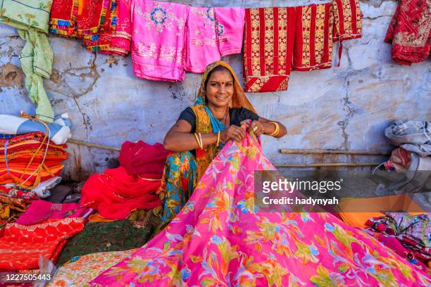 farben von indien - frau verkauft bunte stoffe auf lokalen basar - rajasthani women stock-fotos und bilder
