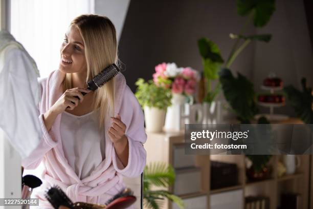 young woman brushing hair - brushing hair stock pictures, royalty-free photos & images