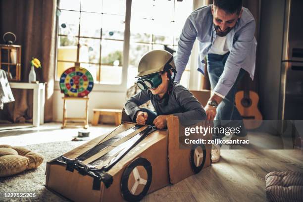 vater und sohn spielen autorennen mit pappkartons - wohngebäude innenansicht stock-fotos und bilder