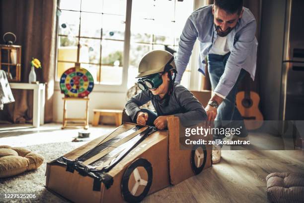 father and son playing car racing with cardboard boxes - family with one child stock pictures, royalty-free photos & images