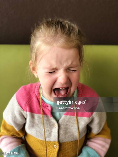 girl sitting on a sofa crying - tantrum stock pictures, royalty-free photos & images