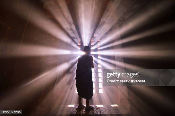 rear view silhouette of a novice monk standing by a window, mandalay, myanmar - spirituelle erleuchtung stock-fotos und bilder