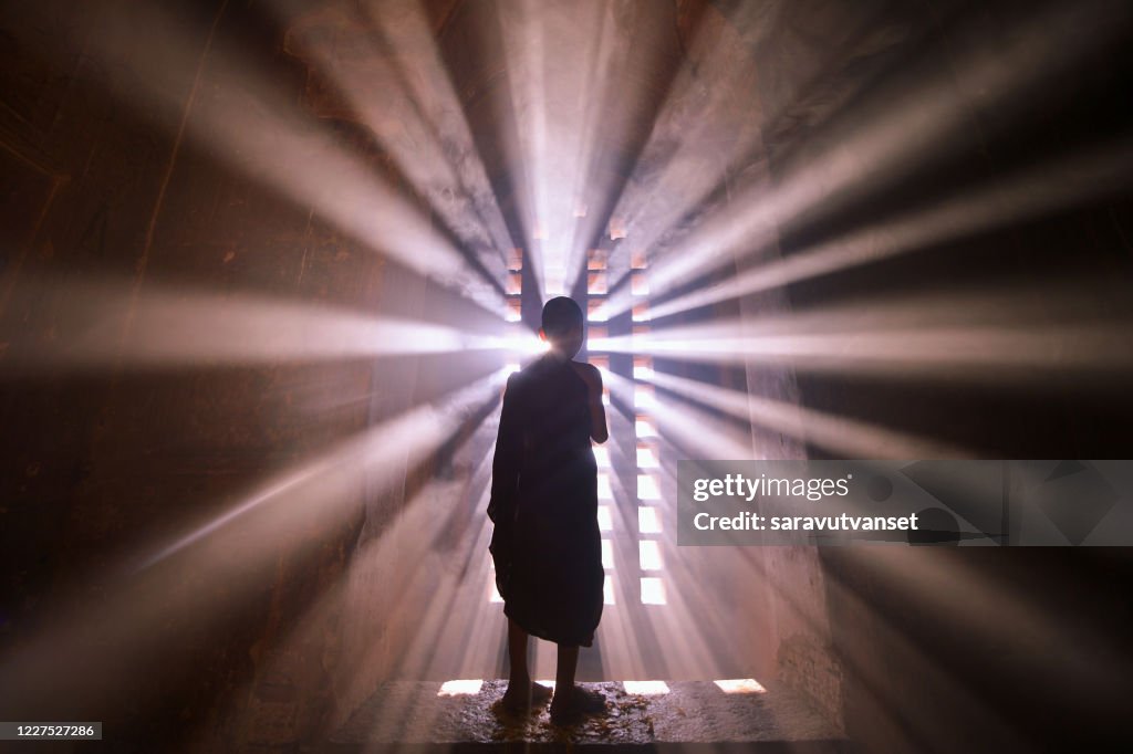 Rear view silhouette of a novice monk standing by a window, Mandalay, Myanmar