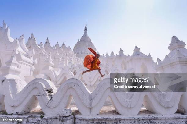 novice monk jumping on traditional temple, myanmar - monk religious occupation stock-fotos und bilder