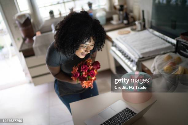 girlfriend receiving flowers / present of her boyfriend and talking to him on internet via laptop at home - zoom birthday stock pictures, royalty-free photos & images