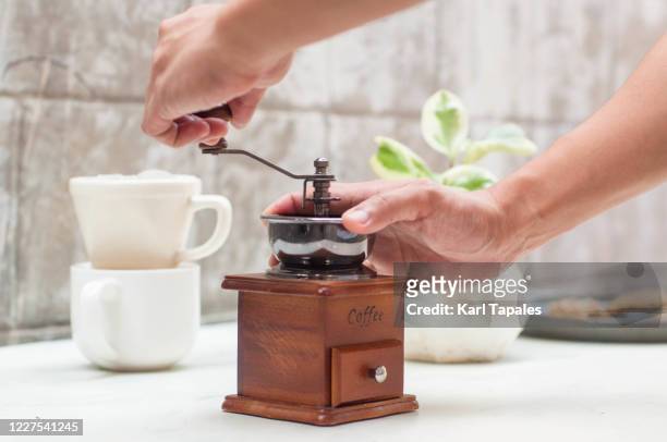 a young person is using an old-fashioned manual coffee mill to make a coffee - coffee grinder stock-fotos und bilder