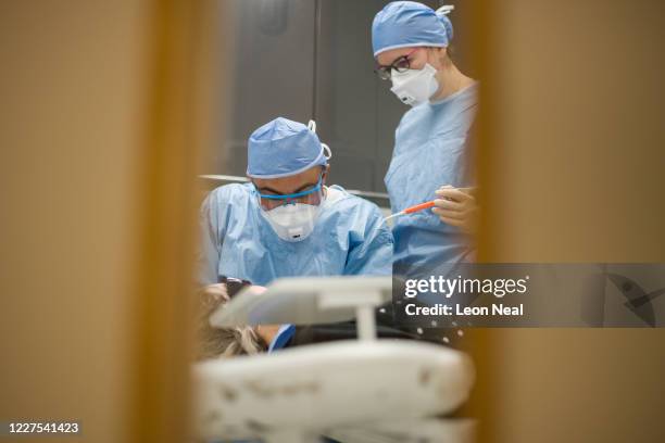 Dentist Fiez Mughal and Dental Nurse Johanna Bartha are seen through a window wearing PPE clothing at East Village dental practice during a procedure...