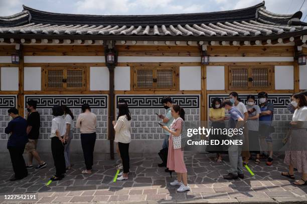Customers queue outside the Tosokchon Samgyetang restaurant in Seoul on July 16, 2020. - South Korea marks 'Chobok', the first day of what is...