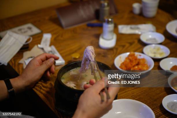 Customer eats a chicken and ginseng soup known as 'samgyetang', at the Tosokchon Samgyetang restaurant in Seoul on July 16, 2020. - South Korea marks...