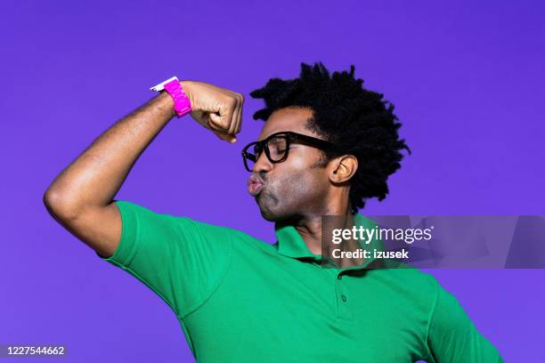 retrato de color de joven funky con bíceps mostrando - flexionar los músculos fotografías e imágenes de stock