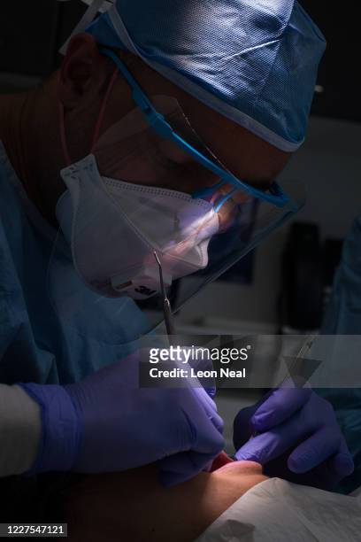 Dentist Fiez Mughal carries out a procedure on a patient in one of the six surgery rooms at East Village dental practice on May 28, 2020 in London,...