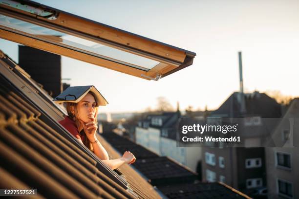 young woman with a book on her head at the window - portare sulla testa foto e immagini stock