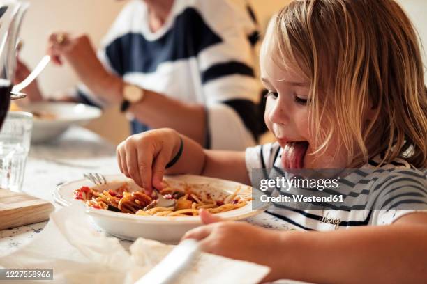 portrait of little girl eating spaghetti - avidità foto e immagini stock