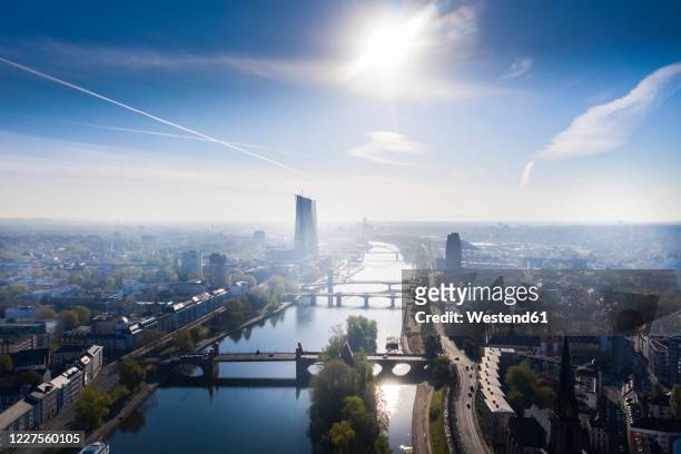 germany, hesse, frankfurt, helicopter view of sun shining over river main and surrounding city buildings - hesse germany stock-fotos und bilder