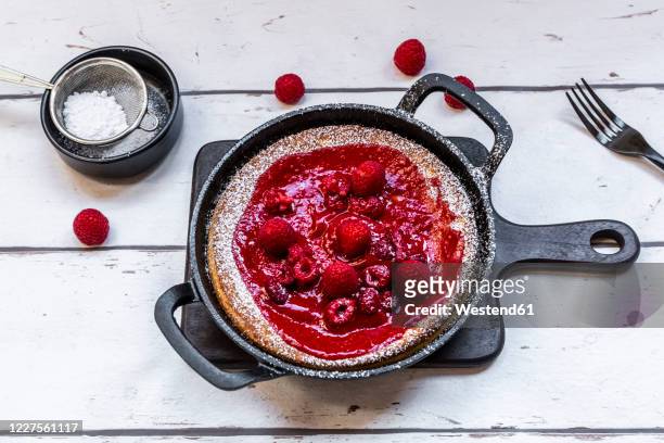 dutch baby pancake with raspberries, raspberry coulis and powdered sugar - dutch pancakes stockfoto's en -beelden