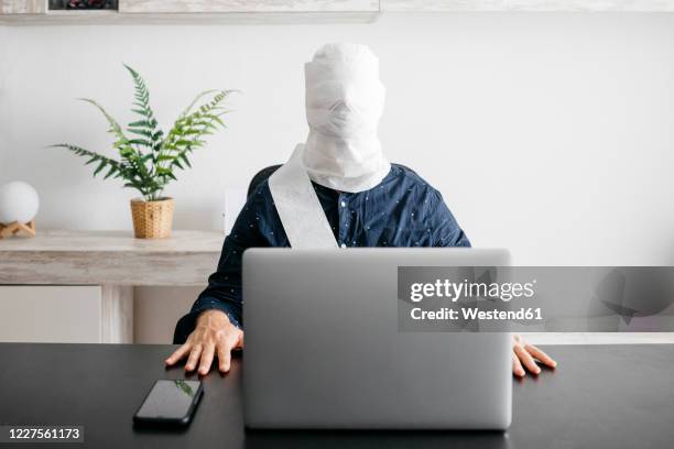 man working at home with his head covered in toilet paper - wrapped in toilet paper stock pictures, royalty-free photos & images