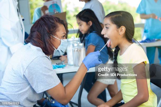 volunteer doctor checks sick girl's throat - social worker mask stock pictures, royalty-free photos & images