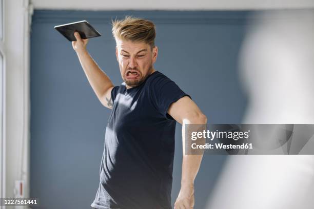 angry man throwing tablet away - hysteria fotografías e imágenes de stock