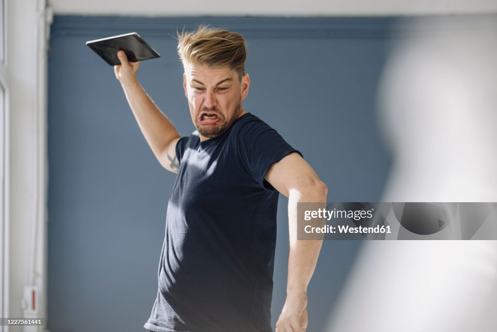 Angry man throwing tablet away