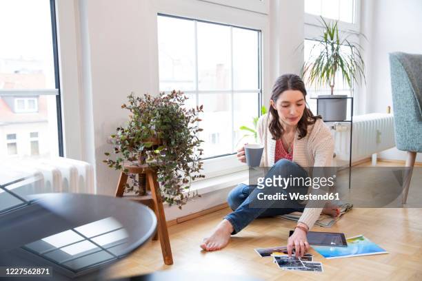 woman sitting on the floor at home looking at photographs - homesick vacation stock pictures, royalty-free photos & images