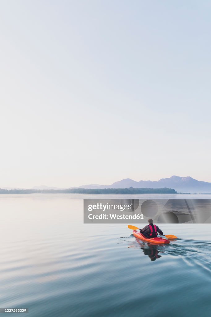 Woman standing on sup board in the morning on a lake, Germany