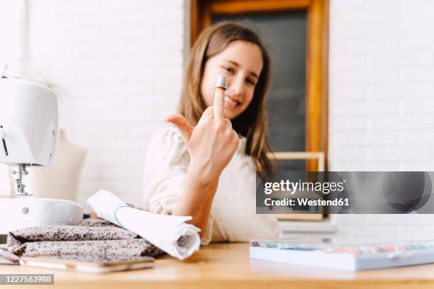 mischievous girl at table with sewing machine giving the finger - kid middle finger imagens e fotografias de stock