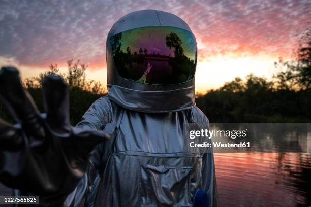 portrait of spacewoman with raising arm at sunset - astronaut hand stock pictures, royalty-free photos & images