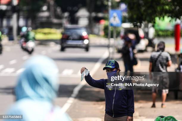 Currency exchange service vendor wearing a protective face mask while waiting for consumers on the sidewalk in Bandung, Indonesia, May 22, 2020....