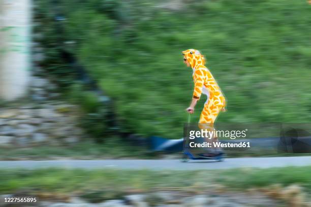 young man wearing giraffe costume on scooter - weird hobbies stock pictures, royalty-free photos & images