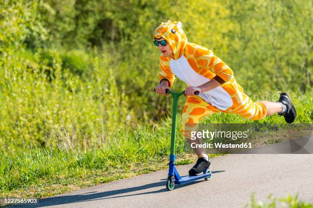young man wearing giraffe costume on scooter - nur erwachsene stock-fotos und bilder