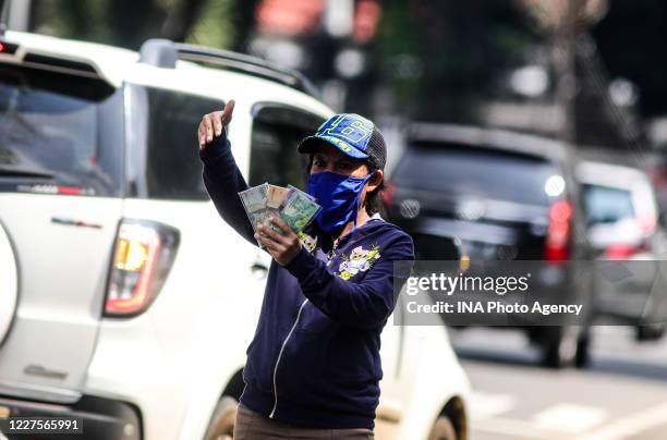 Currency exchange service vendor wearing a protective face mask while waiting for consumers on the sidewalk in Bandung, Indonesia, May 22, 2020....