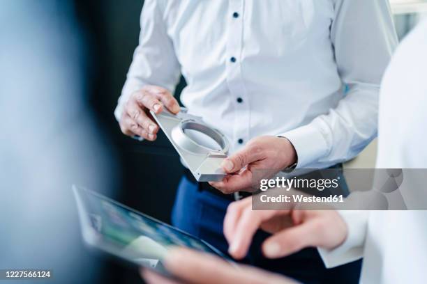close-up of businessman and businesswoman with product and tablet having a work meeting - industriële vormgever stockfoto's en -beelden