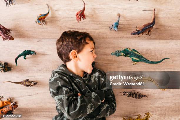 little boy lying on the floor between toy dinosaurs - toy animal - fotografias e filmes do acervo
