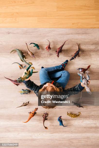 little girl sitting on the floor playing with toy dinosaurs around her, top view - children circle floor stock pictures, royalty-free photos & images