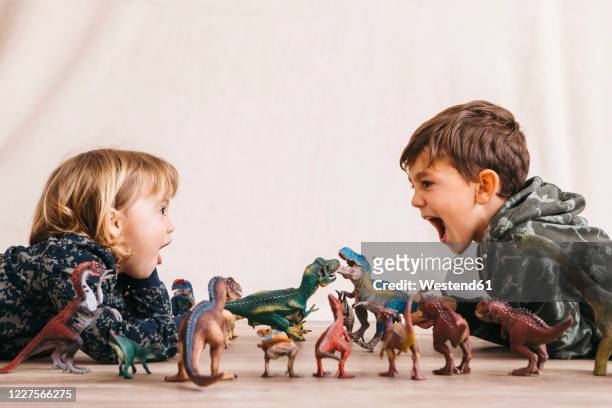 brother and his little sister playing with toy dinosaurs - young tiny girls photos et images de collection