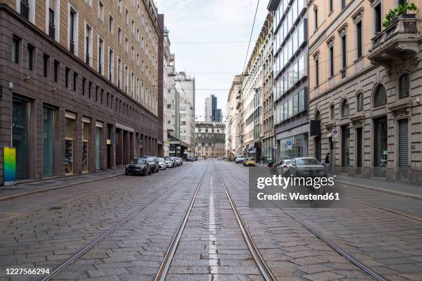 italy, milan, railroad tracks stretching along empty city street during covid-19 outbreak - milan financial district stock pictures, royalty-free photos & images