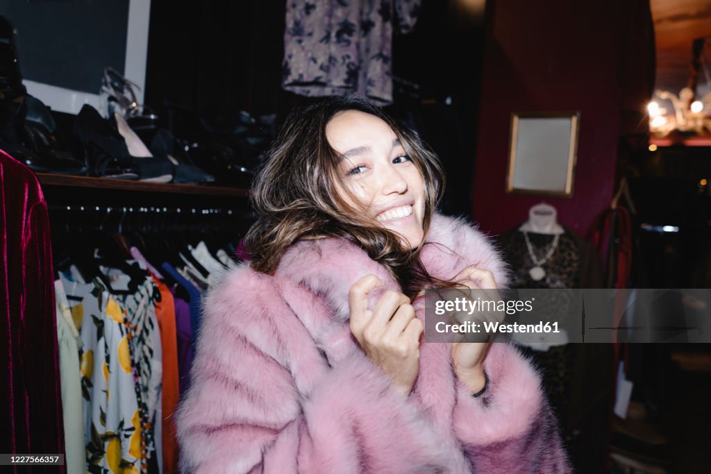 Portrait of smiling woman wearing pink fur jacket at thrift store