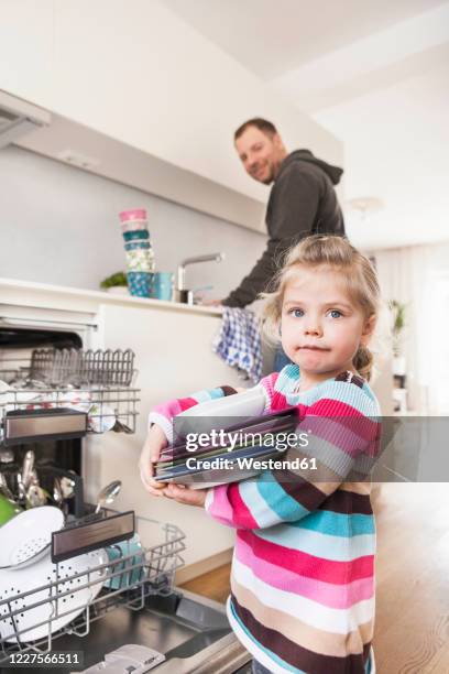 daughter clearing the dishwasher, father in the background - stack of plates stock pictures, royalty-free photos & images