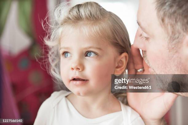 father whispering in dauthter's ear - 2 year old blonde girl father stock pictures, royalty-free photos & images