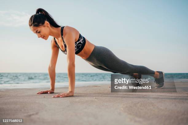 full length of young woman doing push-ups on promenade - push ups stock-fotos und bilder