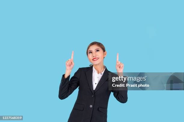 young modern businesswoman confident pose with copy space on top cyan background standing and finger pointing and smile use for business advertisement. - executive smile pointing bildbanksfoton och bilder