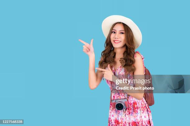 beautiful portrait young asian woman wear hat feeling happiness and gesture hand with camera with travel summer trip in vacation isolated blue background, model tourist asia girl cheerful with journey. - walking away from camera stock pictures, royalty-free photos & images