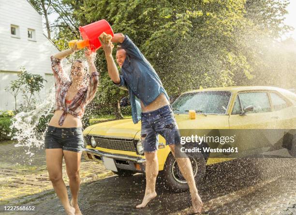 friends washing yellow vintage car in summer having fun - friend mischief stock pictures, royalty-free photos & images