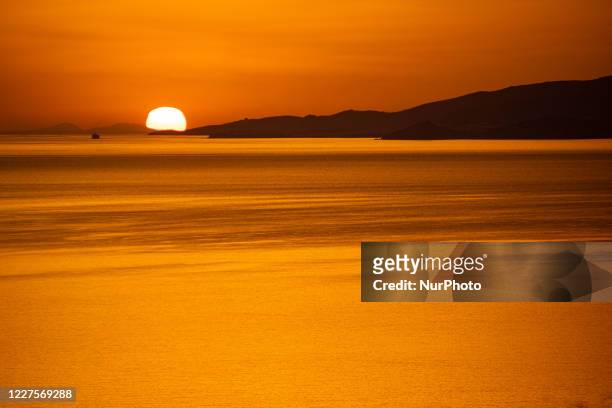 Dreamy sunset during the golden hour before dusk with the sky shifting red, orange and warm colors as the sun goes down behind the Aegean Sea over...