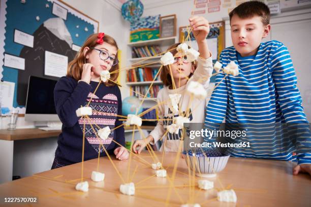 three children setting up construction during a science lesson - expérience scientifique scolaire photos et images de collection