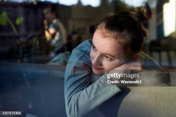 girl on couch at home looking out of window - kinderwunsch stock-fotos und bilder