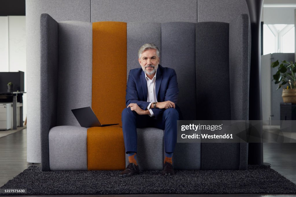 Portrait of mature businessman sitting on couch in office