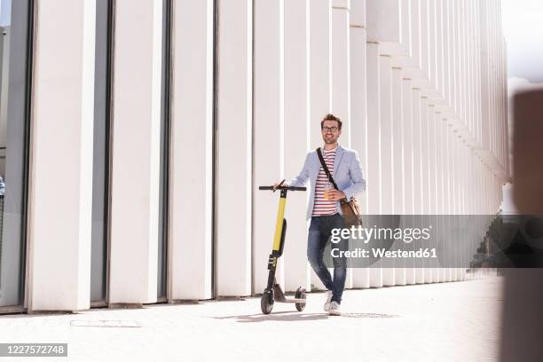 young man with e-scooter and takeaway drink in the city, lisbon, portugal - businessmen casual not phone walking stock pictures, royalty-free photos & images