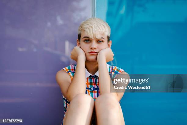 portrait of female teenager wearing colorful dress leaning on multicolored glass pane - blond hair girl stock-fotos und bilder