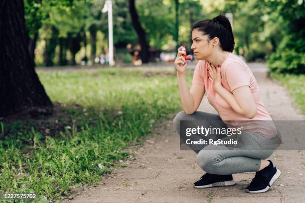 girl using asthma inhaler during jogging - asthma in adults stock pictures, royalty-free photos & images